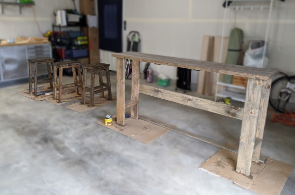 Photograph of homemade wooden bar table and stools in a garage.